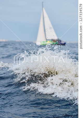 Sailing regatta in the Gulf of Finland at sunset, sailing yacht competing in a race, splashing water from under the boat, teamwork, board the boat Sailing regatta in the Gulf of Finland at sunset, sailing yacht competing in a race, splashing water from under the boat, teamwork, board the boat 127334579