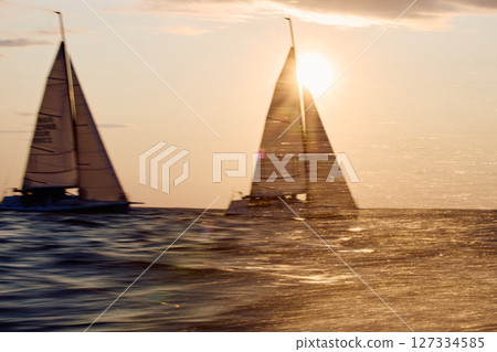 Sailing regatta in the Gulf of Finland at sunset, two sailing yachts competing in a race, splashing water from under the boats, teamwork, board the boat 127334585