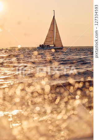 Sailing regatta in the Gulf of Finland at sunset, sailing yacht competing in a race, splashing water from under the boat, teamwork, board the boat Sailing regatta in the Gulf of Finland at sunset, sailing yacht competing in a race, splashing water from under the boat, teamwork, board the boat 127334593