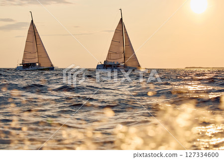 Sailing regatta in the Gulf of Finland at sunset, two sailing yachts competing in a race, splashing water from under the boats, teamwork, board the boat 127334600