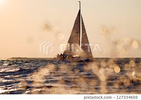 Sailing regatta in the Gulf of Finland at sunset, sailing yacht competing in a race, splashing water from under the boat, teamwork, board the boat Sailing regatta in the Gulf of Finland at sunset, sailing yacht competing in a race, splashing water from under the boat, teamwork, board the boat 127334608