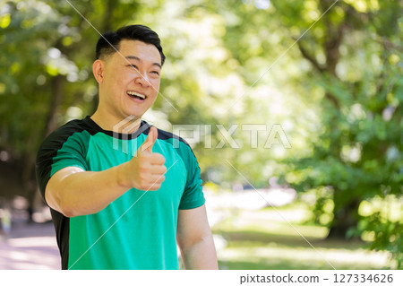 Athletic smiling runner fit man, happy about marathon achievement showing thumb up like gesture 127334626