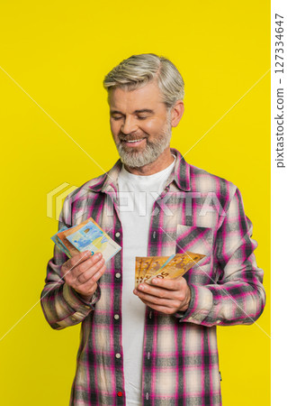 Mature man counting money euro cash, satisfied grin, expressing gain bonus salary financial reward Mature man counting money euro cash, satisfied grin, expressing gain bonus salary financial reward 127334647