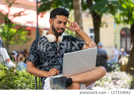Indian young man using laptop computer celebrating win online good message news in urban city street 127334662