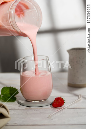 Pouring strawberry smoothie. Fruit healthy milkshake glass with fresh berries. Pouring strawberry smoothie. Fruit healthy milkshake glass with fresh berries. 127334933