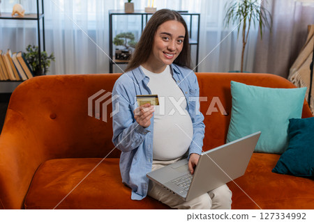 Online shopping buying pregnant woman sitting on home sofa making purchase using laptop credit card 127334992