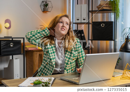 Business woman suffers from spine neck muscle pain at home office workplace working on laptop Business woman suffers from spine neck muscle pain at home office workplace working on laptop 127335015