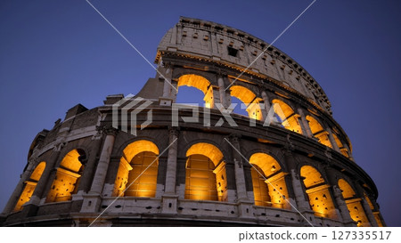 Warm lights illuminate the colosseum's arches against a darkening blue sky, showcasing the ancient amphitheater's grandeur and timeless beauty in the heart of rome Warm lights illuminate the colosseum's arches against a darkening blue sky, showcasing the ancient amphitheater's grandeur and timeless beauty in the heart of rome 127335517