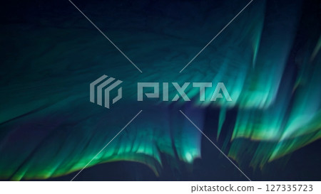 Aurora borealis illuminating the night sky with vibrant hues of green and purple, creating a mesmerizing spectacle over a snow covered terrain 127335723