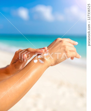 Woman's hands applying sunscreen Woman's hands applying sunscreen 127336525
