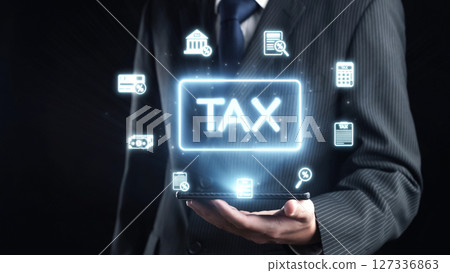 Businessman Holding Tablet with Tax Icons and Symbols Representing Digital Financial Services and Taxation Concepts in a Dark Background. Qubit 127336863