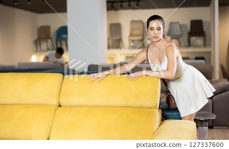 Adult happy smiling female touching sofa in the furniture store before buying 127337600