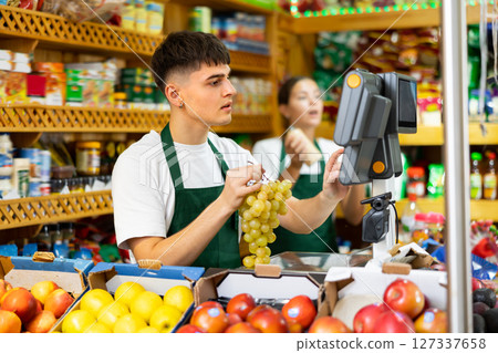Male shopping assistant weighing grapes in shop 127337658