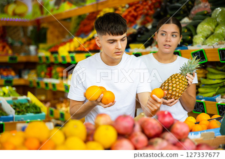 Young husband and wife choose fresh fruit together in grocery supermarket Young husband and wife choose fresh fruit together in grocery supermarket 127337677