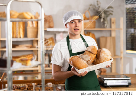 male baker sells croissants, shows off a variety of crescent-shaped buns. male baker sells croissants, shows off a variety of crescent-shaped buns. 127337812