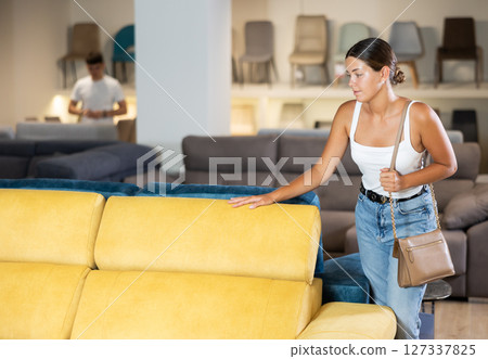 Young woman chooses sofa in store 127337825