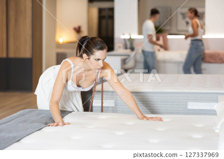 Young woman choosing convenient mattress in furniture shop 127337969