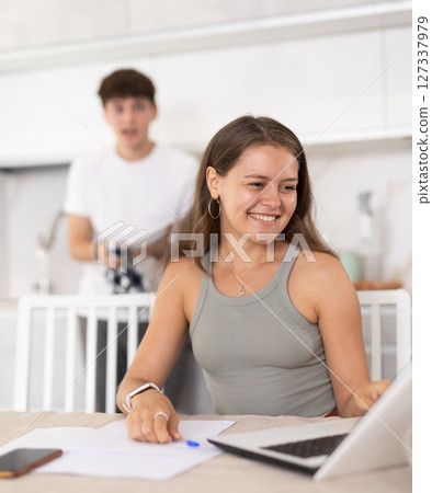 Young guy smiling and chatting with woman working at laptop Young guy smiling and chatting with woman working at laptop 127337979