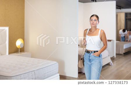 Young woman looking around in bedroom department 127338173