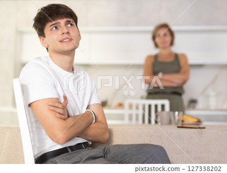 Adult woman quarreling with young guy in kitchen Adult woman quarreling with young guy in kitchen 127338202