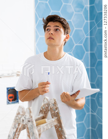 Motivated guy taking notes while working on renovation of house Motivated guy taking notes while working on renovation of house 127338206