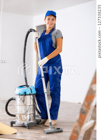 Portrait of a young girl worker with a vacuum cleaner 127338235