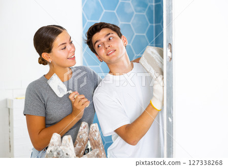 Young couple laying ceramic tiles on walls during home renovation 127338268