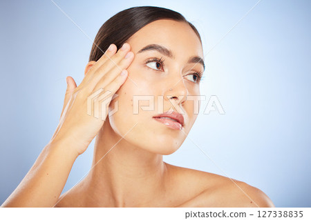 Face, beauty and skincare with model woman in studio on a blue background thinking about natural treatment. Makeup, wellness and aesthetic with an attractive young female posing to promote a product 127338835