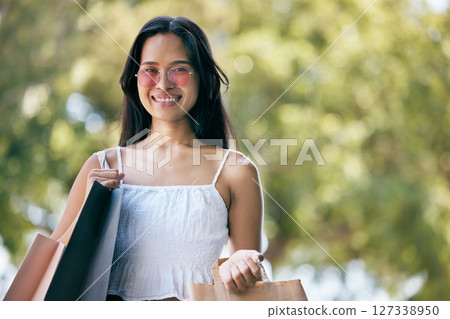 Woman, fashion and shopping with a smile while outdoor with a green background after buying retail products on sale, promotion and discount. Face portrait of a happy customer with consumer bags Woman, fashion and shopping with a smile while outdoor with a green background after buying retail products on sale, promotion and discount. Face portrait of a happy customer with consumer bags 127338950