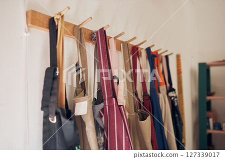 Clothing rack, apron and workshop of clothes hanging on a creative studio wall for art, style or design. Closeup of aprons or work equipment for artistic development on rack for business startup Clothing rack, apron and workshop of clothes hanging on a creative studio wall for art, style or design. Closeup of aprons or work equipment for artistic development on rack for business startup 127339017