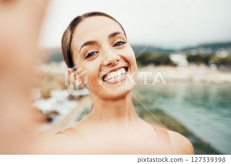 Selfie, beach and travel with a woman tourist taking a picture outdoor during summer vacation or holiday. Portrait, face and smile with an attractive young female happy on the coast by the sea 127339398