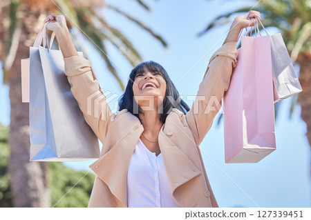 Success, shopping bag and celebration of woman in city after buying clothes on discount on Black Friday. Fashion, sales deal and happy female holding gifts and celebrating after purchase at mall. Success, shopping bag and celebration of woman in city after buying clothes on discount on Black Friday. Fashion, sales deal and happy female holding gifts and celebrating after purchase at mall. 127339451