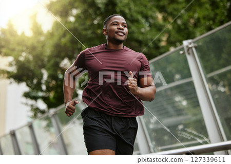 Black man, fitness and running in park for healthy workout, exercise or cardio in the nature outdoors. Happy African American male runner enjoying a jog, run or exercising for health and wellness 127339611