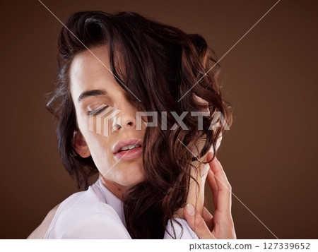 Beauty, hair care and woman in a studio with healthy, shiny and curly hair style from a salon. Health, wellness and model with keratin hair treatment isolated by brown background 127339652