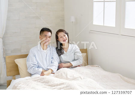Middle-aged couple on the bed, smiling, portrait 127339707