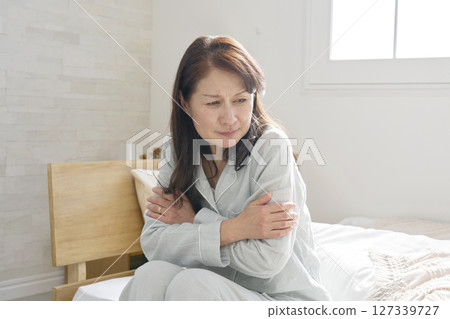 Middle-aged woman in pajamas feeling cold Middle-aged woman in pajamas feeling cold 127339727