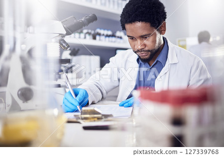 Black man writing report for science study, scientist in lab for research to test and experiment for scientific innovation. Biotechnology in laboratory, focus and knowledge, pen and checklist. Black man writing report for science study, scientist in lab for research to test and experiment for scientific innovation. Biotechnology in laboratory, focus and knowledge, pen and checklist. 127339768