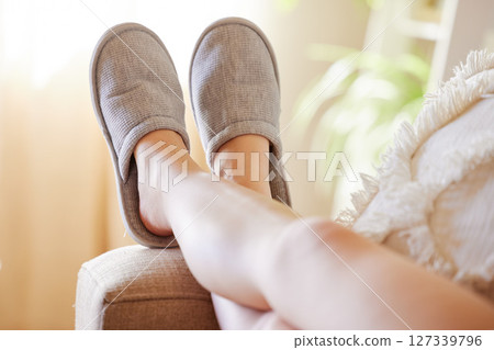 Legs, relax and woman in slippers on sofa resting on weekend at home. Shoes, freedom and female relaxing, lying and spending time alone on comfy, cozy and comfortable couch in living room of house. 127339796