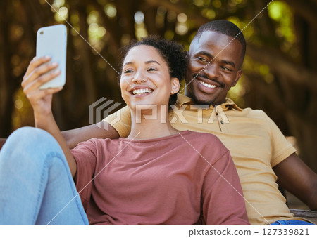 Black couple, phone and selfie with smile at outdoor nature park for travel, happiness and social media profile picture content update. Happy man and woman with 5g network connection on vacation date Black couple, phone and selfie with smile at outdoor nature park for travel, happiness and social media profile picture content update. Happy man and woman with 5g network connection on vacation date 127339821