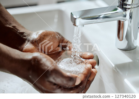 Black man, house bathroom or washing hands with water for healthcare wellness, hygiene maintenance or home self care. Zoom, wet or sink tap for cleaning, skincare grooming or bacteria safety routine Black man, house bathroom or washing hands with water for healthcare wellness, hygiene maintenance or home self care. Zoom, wet or sink tap for cleaning, skincare grooming or bacteria safety routine 127340120