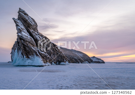 Scenery view of the Dragon tail rock before sunrise. It's located at Ogoy island in frozen lake Baikal, Russia. Scenery view of the Dragon tail rock before sunrise. It's located at Ogoy island in frozen lake Baikal, Russia. 127340562