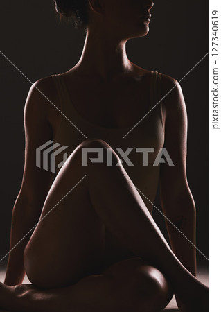 Beauty, body and silhouette of a woman in a studio with a creative, mysterious and seductive aesthetic. Art, fantasy and shadow figure of a female model with a sexy pose by a dark black background. Beauty, body and silhouette of a woman in a studio with a creative, mysterious and seductive aesthetic. Art, fantasy and shadow figure of a female model with a sexy pose by a dark black background. 127340619