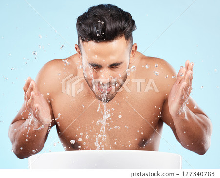 Face, water splash and skincare of man cleaning in studio isolated on a blue background. Hygiene, water drops and male model washing, bathing or grooming for healthy skin, facial wellness or beauty. Face, water splash and skincare of man cleaning in studio isolated on a blue background. Hygiene, water drops and male model washing, bathing or grooming for healthy skin, facial wellness or beauty. 127340783