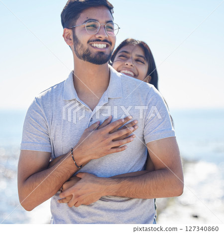 Hug, happy young couple at beach with travel and care on summer holiday by ocean, commitment and support outdoor. Partner, embrace and relationship with romantic date, man and woman on vacation 127340860