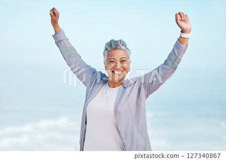 Fitness, hands in air and senior woman for exercise, fitness or workout portrait goals, success and achievement on blue sky mockup. Winner, freedom and healthy celebration of elderly runner in nature 127340867