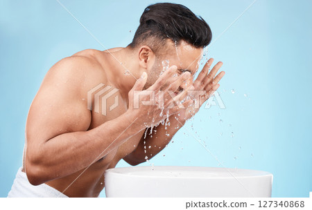 Clean, grooming and man washing face with water for skincare, morning hygiene and care of body on a blue studio background. Beauty, wellness and model with a facial water splash for cleaning 127340868