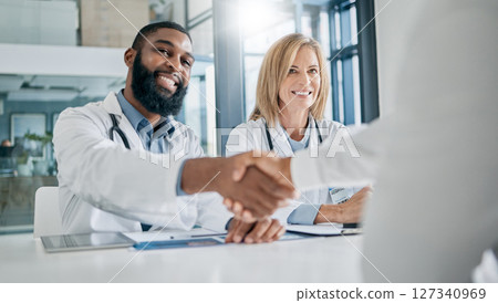 Handshake, partnership or happy doctors in a meeting after successful medical surgery or reaching healthcare goals. Teamwork, woman or black man smiles shaking hands with a worker in hospital office Handshake, partnership or happy doctors in a meeting after successful medical surgery or reaching healthcare goals. Teamwork, woman or black man smiles shaking hands with a worker in hospital office 127340969