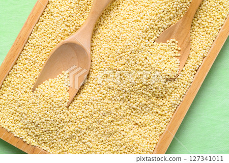 Yellow millet grain in wooden plate with scoop, Food ingredient, Top view 127341011