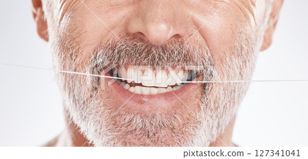 Dental, floss and mouth of senior man in studio isolated on a gray background. Hygiene, cleaning and elderly male model with product flossing teeth for oral wellness, tooth care and healthy gums. Dental, floss and mouth of senior man in studio isolated on a gray background. Hygiene, cleaning and elderly male model with product flossing teeth for oral wellness, tooth care and healthy gums. 127341041