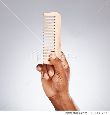 Hand, wood comb and studio for beauty, grooming and self care cosmetics by grey background. Black man, organic wooden product and recycle material for wellness, skincare and hair care with self love Hand, wood comb and studio for beauty, grooming and self care cosmetics by grey background. Black man, organic wooden product and recycle material for wellness, skincare and hair care with self love 127341254